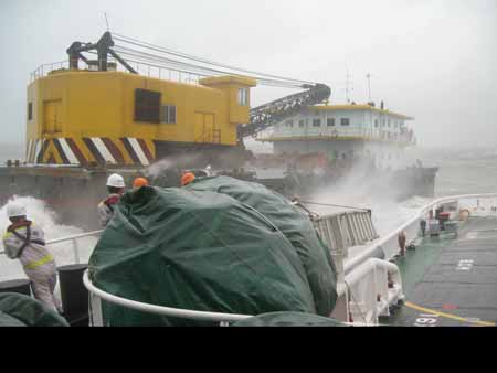 A vessel rescues an engineering barge in danger on the sea off Shantou in south China's Guangdong Province, July 19, 2009. The engineering barge with its seven crew members was successfully rescued on July 19, after it was wrapped on the sea due to typhoon Molave on July 18.