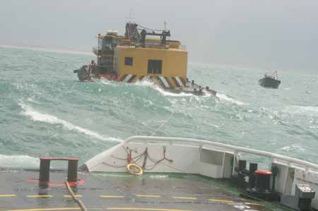  A vessel rescues an engineering barge in danger on the sea off Shantou in south China's Guangdong Province, July 19, 2009. The engineering barge with its seven crew members was successfully rescued on July 19, after it was wrapped on the sea due to typhoon Molave on July 18. 