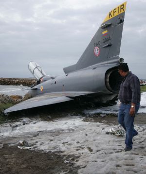 An investigator inspects the Kfir fighter plane crash site at an airport in Cartagena, Colombia, on July 20, 2009. Two pilots aboard the plane survived the accident Monday. 