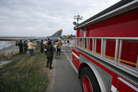Investigators and rescuers inspect the Kfir fighter plane crash site at an airport in Cartagena, Colombia, on July 20, 2009. Two pilots aboard the plane survived the accident Monday. 