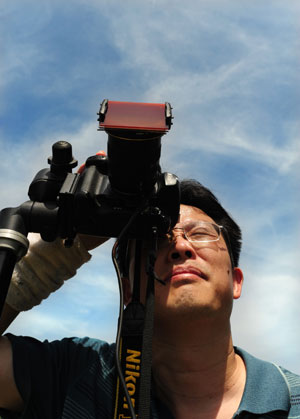 A Chinese photographer adjusts his camera lens in preparation for the next day's total solar eclipse observation on a hill near the Three Gorges Dam near Zigui County in central China's Hubei Province, on July 21, 2009.