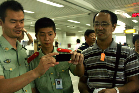 Two Chinese police officers (L) check a pair of special glasses carried by a Hong Kong tourist in preparation for the next day's total solar eclipse observation upon his arrival at Hangzhou International Airport in Hangzhou, capital city of east China's Zhejiang Province, on July 21, 2009.