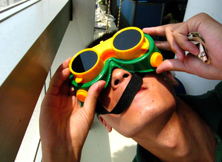 A young Chinese tests a pair of brand-new glasses in preparation for the next day's total solar eclipse observation in Hefei, capital city of east China's Anhui Province, on July 21, 2009. 