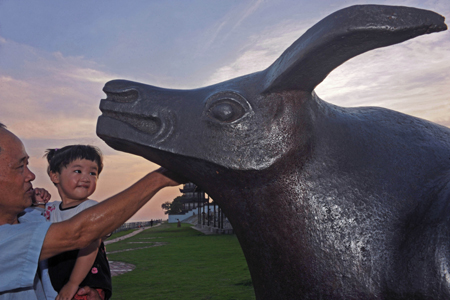 Resident Chen Jinwen and his granddaughter look at the iron bull, a mythical character legendarily putting down the Qiantang River spring tide, in Yanguan Town of Haining City under Jiaxing, east China&apos;s Zhejiang Province, on July 19, 2009. People living along China&apos;s Yangtze River will have a chance to witness the longest total solar eclipse this century on July 22.