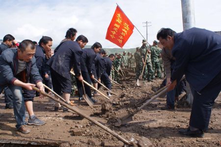 Local Chinese and armed police officers clear mud left by a flood on a road on July 21, 2009 after a heavy rainstorm hit Maqu County in northwest China's Gansu Province, killing at least five people. 