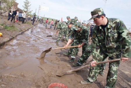 Chinese armed police officers clear mud left by a flood on a road on July 21, 2009 after a heavy rainstorm hit Maqu County in northwest China's Gansu Province, killing at least five people.