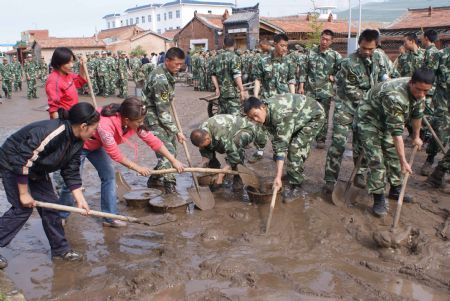 Chinese armed police officers and local people clear mud left by a flood on a road on July 21, 2009 after a heavy rainstorm hit Maqu County in northwest China's Gansu Province, killing at least five people. 