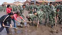 Chinese armed police officers and local people clear mud left by a flood on a road on July 21, 2009 after a heavy rainstorm hit Maqu County in northwest China's Gansu Province, killing at least five people.