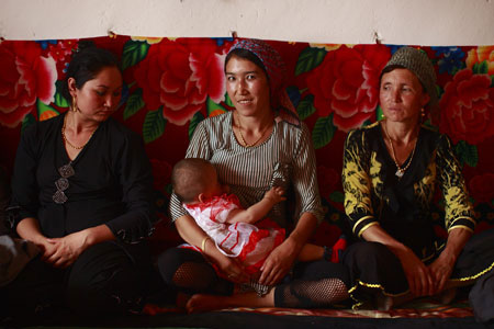 A woman feeds her child at a Kirgiz wedding ceremony in a summer pasture in Wensu County of northwest China's Xinjiang Uygur Autonomous Region, July 19, 2009. (Xinhua/Cai Yang)