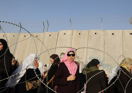 File photo taken on Sepember 26, 2008 shows Palestinians waiting beside the separation fence to cross the Qalandiya checkpoint for Friday prayers during the Muslim fasting month of Ramadan outside the West Bank city of Ramallah. 