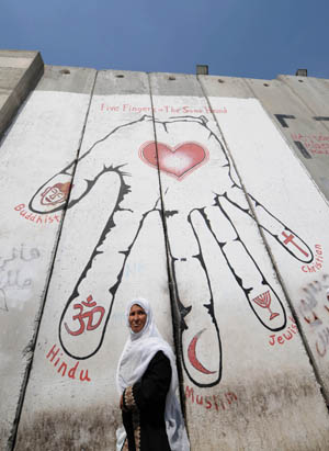 File photo taken on Sepember 12, 2009 shows a Palestinian walking past the separation fence at Rachel's Tomb checkpoint in the West Bank city of Bethlehem. Israeli Prime Minister Benjamin Netanyahu on Wednesday said that Israel is not to demolish the separation fence in the West Bank, as the barrier constitutes 'a critical component' of his country's security.