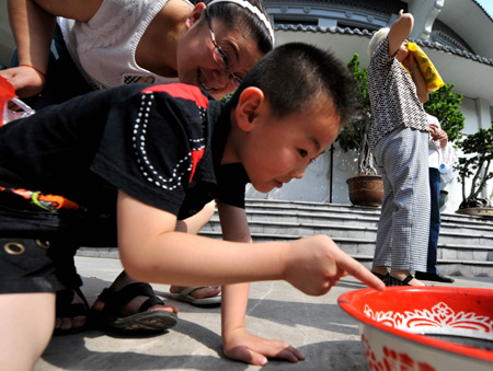 A child observes the sun eclipse through water reflection in Taiyuan, capital of China's Shanxi Province, on July 22, 2009.