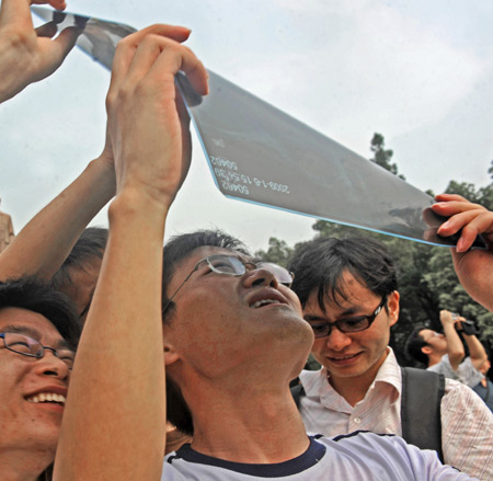 Local residents witness the solar eclipse through an X-ray film in Jiujiang, south China's Jiangxi Province, on July 22, 2009.