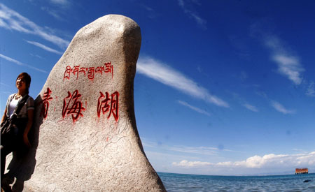 A tourist poses for a picture beside the Qinghai Lake in northwest China's Qinghai Province, on July 21, 2009. As the boom season for tourism began, more and more tourists arrived here to enjoy the natural scenery. 
