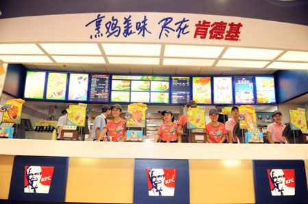 Staff members of a KFC store in the international bazar wait for customers in Urumqi, capital of northwest China's Xinjiang Uygur Autonomous Region, on July 23, 2009. The KFC store in the international bazar, which was closed after the July 5 riot, was reopened on Thursday. 