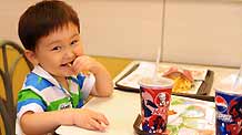 A kid eats at the KFC store in the international bazar in Urumqi, capital of northwest China's Xinjiang Uygur Autonomous Region, on July 23, 2009. The KFC store in the international bazar, which was closed after the July 5 riot, was reopened on Thursday.