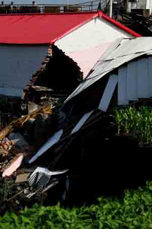 Photo taken on July 23, 2009 shows the collapsed work shed at the Xinyongfeng Coal Mine where a flooding accident took place in Jixi City, northeast China's Heilongjiang Province. More than 200 rescuers were searching for 23 miners who were trapped underground after a flooding accident late Wednesday night at the coal mine in Jixi City. Preliminary investigation showed heavy rain was to blame for a cave-in in the mine, which trapped the miners. 