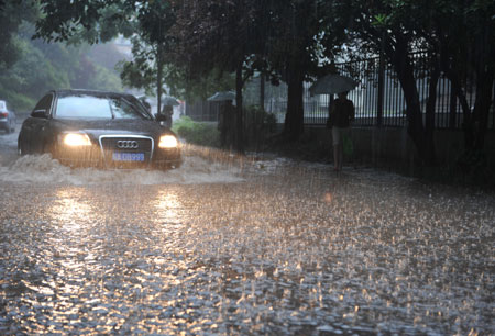 A vehicle moves on a flooded street as a heavy rain hits Hefei, capital city of east China&apos;s Anhui Province, on July 23, 2009. 
