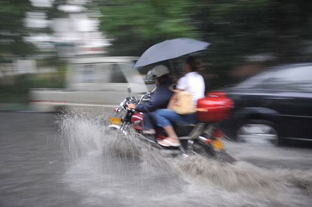 A motor cycle and cars drive on a flooded street as a heavy rain hits Hefei, capital city of east China&apos;s Anhui Province, on July 23, 2009. 