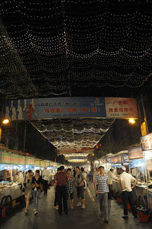 People walk along the street at the most famous night fair in Urumqi, capital of northwest China's Xinjiang Uygur Autonomous Region, on July 25, 2009. The Wuyi Starlight night fair, the biggest and most famous night fair in Urumqi, reopened here on July 21 for the first time since the deadly July 5 riot in the city. 