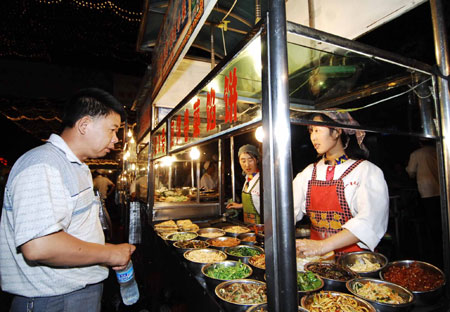 Vendors sell local snacks at the most famous night fair in Urumqi, capital of northwest China's Xinjiang Uygur Autonomous Region, on July 25, 2009. The Wuyi Starlight night fair, the biggest and most famous night fair in Urumqi, reopened here on July 21 for the first time since the deadly July 5 riot in the city. 