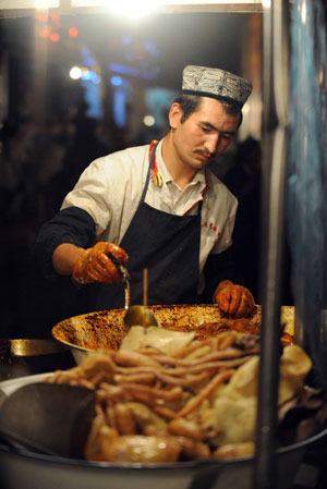 A vendor makes snacks at the most famous night fair in Urumqi, capital of northwest China's Xinjiang Uygur Autonomous Region, on July 25, 2009. The Wuyi Starlight night fair, the biggest and most famous night fair in Urumqi, reopened here on July 21 for the first time since the deadly July 5 riot in the city.