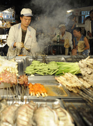 A vendor makes snacks at the most famous night fair in Urumqi, capital of northwest China's Xinjiang Uygur Autonomous Region, on July 25, 2009. The Wuyi Starlight night fair, the biggest and most famous night fair in Urumqi, reopened here on July 21 for the first time since the deadly July 5 riot in the city.