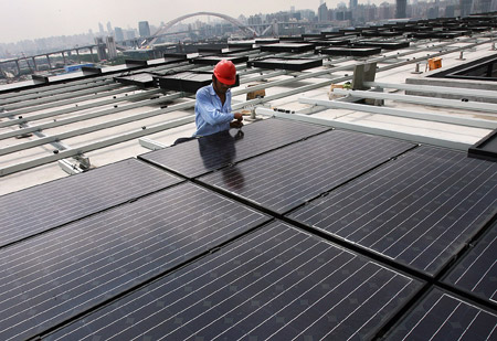 A worker fixes solar energy panels on the top floor of the Chinese Pavilion at the Shanghai Expo Site, Shanghai, east China, on July 25, 2009.