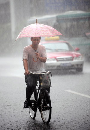 A man rides a bicycle in the rain in Guangzhou, south China's Guangdong Province, on July 28, 2009. 