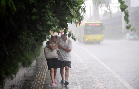 AA couple walks in the rain in Guangzhou, south China's Guangdong Province, on July 28, 2009. 