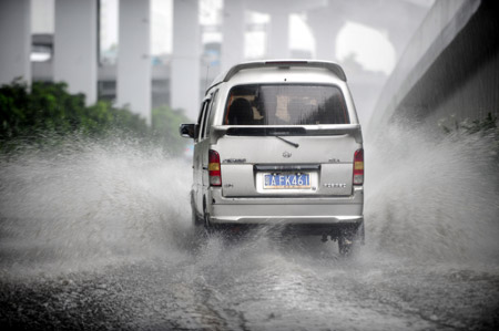 A car runs in the rain in Guangzhou, south China's Guangdong Province, on July 28, 2009.