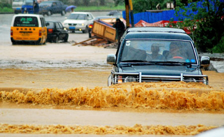 Vehicles drive in deep water on a flooded street as a heavy rainstorm hits Jiujiang city in east China's Jiangxi Province, on July 29, 2009. Local emergency department employees of the city are on standby to answer emergent calls as some local streets were flooded.