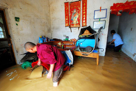 Local residents clear water out of their flooded house after a heavy rainstorm hit Jiujiang city in east China's Jiangxi Province, on July 29, 2009. Local emergency department employees of the city are on standby to answer emergent calls as some local streets were flooded. 