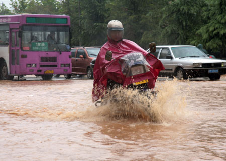 A man drives a motorcycle on a flooded street as a heavy rainstorm hits Jiujiang city in east China's Jiangxi Province, on July 29, 2009. Local emergency department employees of the city are on standby to answer emergent calls as some local streets were flooded. 