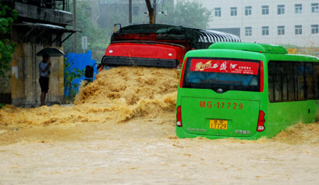 A heavy truck and a bus drive in deep water on a flooded street as a heavy rainstorm hits Jiujiang city in east China's Jiangxi Province, on July 29, 2009. Local emergency department employees of the city are on standby to answer emergent calls as some local streets were flooded.