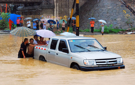  Local residents push a stranded pick-up out of deep water on a flooded street as a heavy rainstorm hits Jiujiang city in east China's Jiangxi Province, on July 29, 2009. Local emergency department employees of the city are on standby to answer emergent calls as some local streets were flooded. 