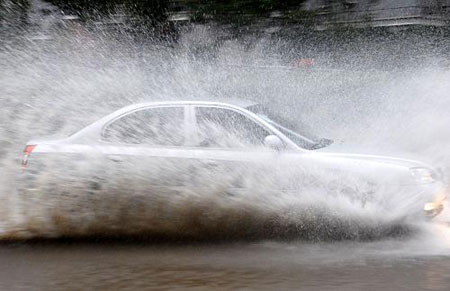 A car drives in water after a heavy rain hit Shanghai, China, on July 30, 2009. A summer heavy rain which triggered red alert hit Shanghai city on Thursday. 