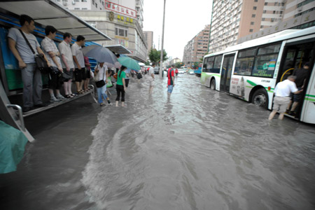 People get on the bus at a flooded section of the Xietu Road in Shanghai, China, on July 30, 2009.