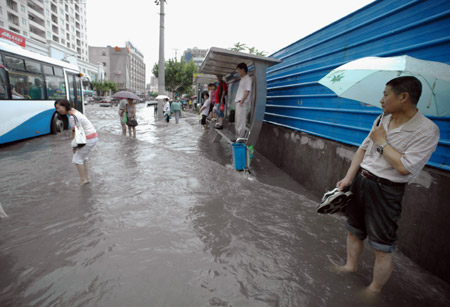 People wait for bus at a flooded section of the Xietu Road in Shanghai, China, on July 30, 2009.