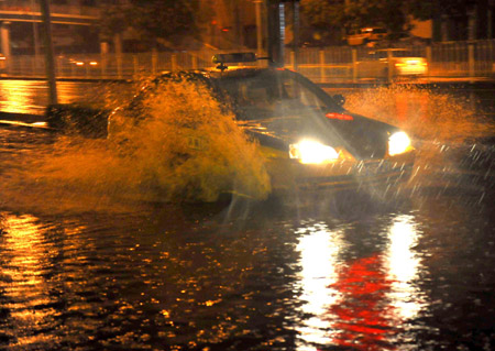 A taxi runs on a flooded street in Beijing, capital of China, on July 31, 2009. A heavy rain hit Beijing on Thursday evening and caused traffic jam. 