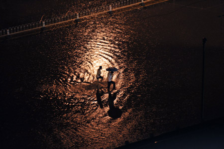 People walk on a flooded street in Beijing, capital of China, on July 31, 2009. 