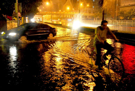 A man rides a bike on a flooded street in Beijing, capital of China, on July 31, 2009. A heavy rain hit Beijing on Thursday evening and caused traffic jam.