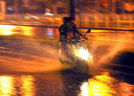 A motorbike runs on a flooded street in Beijing, capital of China, on July 31, 2009. A heavy rain hit Beijing on Thursday evening and caused traffic jam.