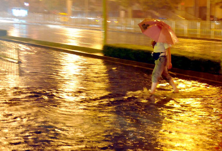 A man walks on a flooded street in Beijing, capital of China, on July 31, 2009. A heavy rain hit Beijing on Thursday evening and caused traffic jam. 