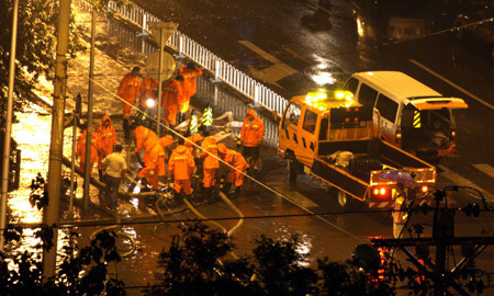 Rescuers work on a flooded street in Beijing, capital of China, on July 31, 2009. A heavy rain hit Beijing on Thursday evening and caused traffic jam.