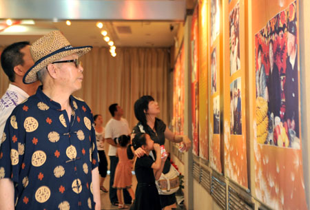 Citizens view pictures at the photo exhibition titled 'We Are One Family' at the Museum of Urumqi, northwest China's Xinjiang Uygur Autonomous Region, on August 1, 2009. 