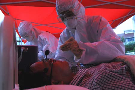 Chinese medics inspect a &apos;patient&apos; of influenza A/H1N1 during a drill for the flu prevention in Xiuning County of Huangshan, in east China&apos;s Anhui Province, on Aug.2, 2009. 