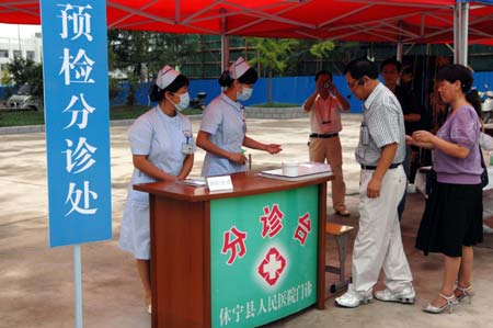 Chinese medics receive a &apos;patient&apos; of influenza A/H1N1 during a drill for the flu prevention in Xiuning County of Huangshan, in east China&apos;s Anhui Province, on Aug.2, 2009.