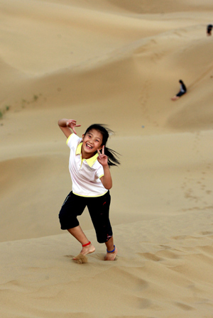 A girl plays on a sand hill in Wuhai City, north China&apos;s Inner Mongolia Autonomous Region, on August 2, 2009. Lots of tourists have fun on sand hills at the weekend.