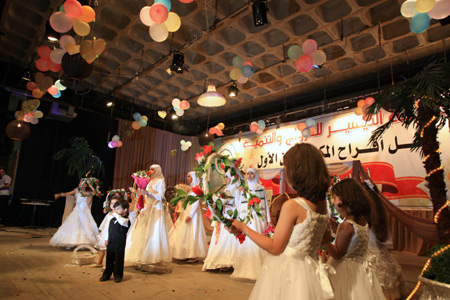 Palestinian children, dressed in bride clothes, sing during a collective wedding party which involved 80 grooms and brides in Gaza city on August 2, 2009.